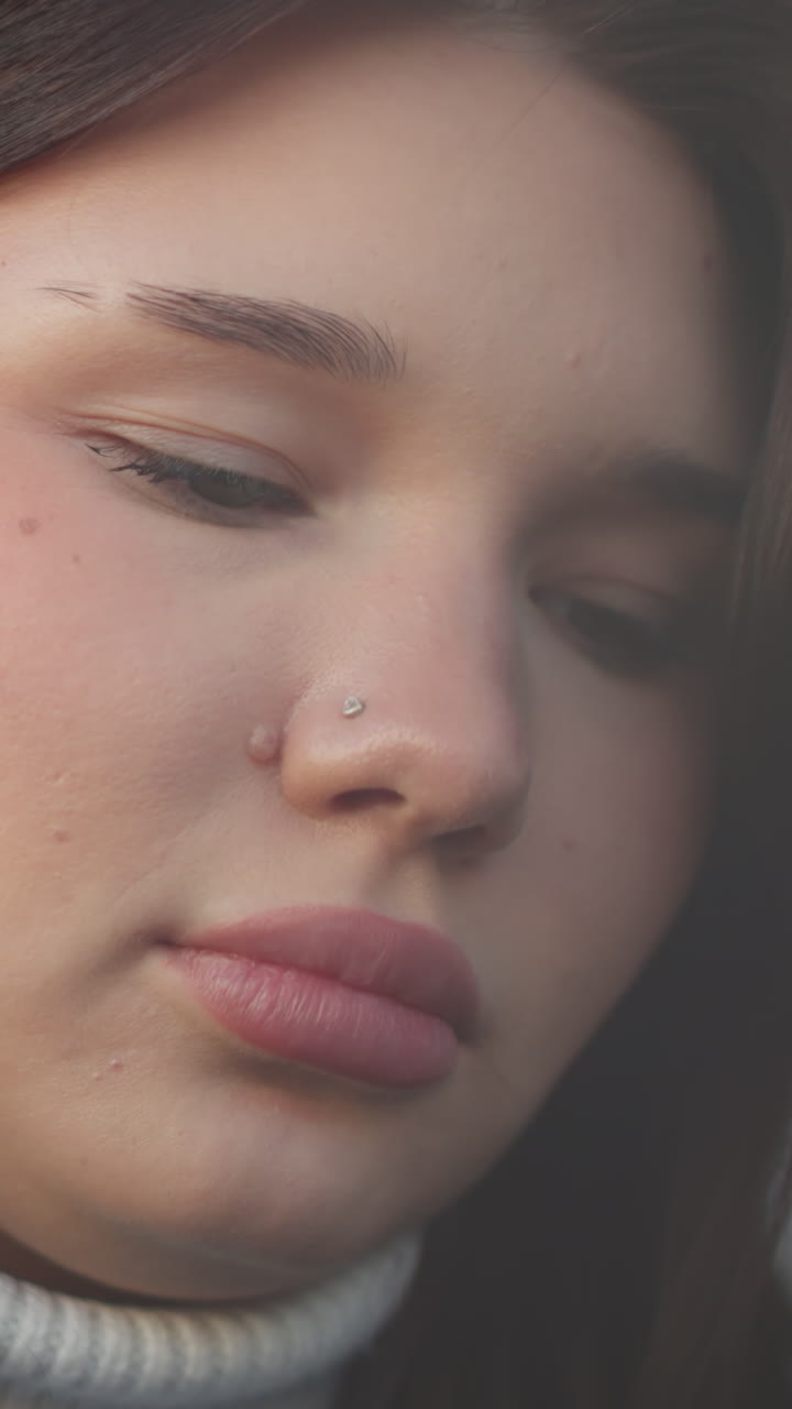 Close-up of woman with pink lips focusing on something in front of her, softly illuminated with blurred background, showcasing her gentle expression and attention