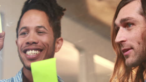 Smiling-casual-business-workers-writing-on-sticky-notes