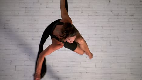 primer plano de una mujer deportiva haciendo yoga aéreo o baile aéreo mientras cuelga y gira, concepto de fitness