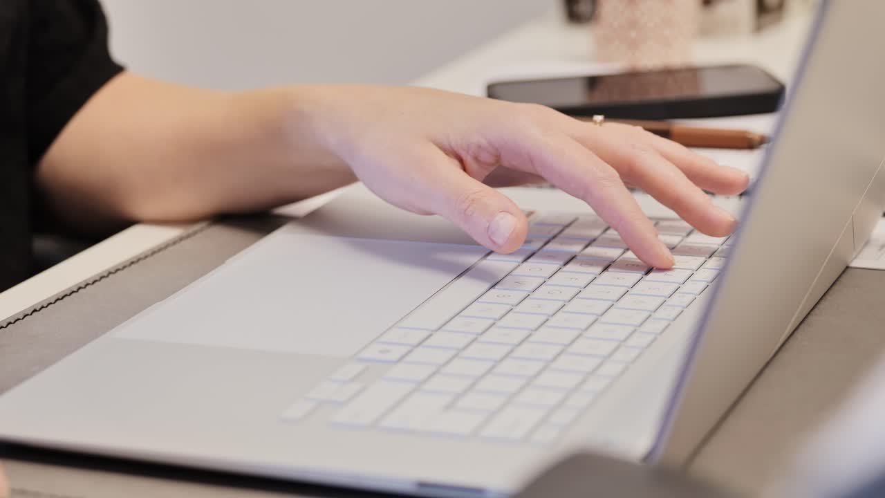 Woman with ring typing on stylish pale computer keyboard, cinematic detail