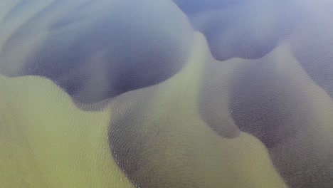 aerial top down shot of olfusa river with dark pattern underwater during sunny day on iceland