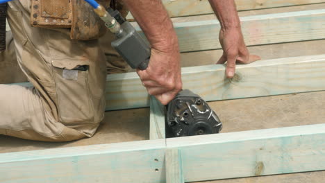 experienced housing frame carpenter uses nail gun on site