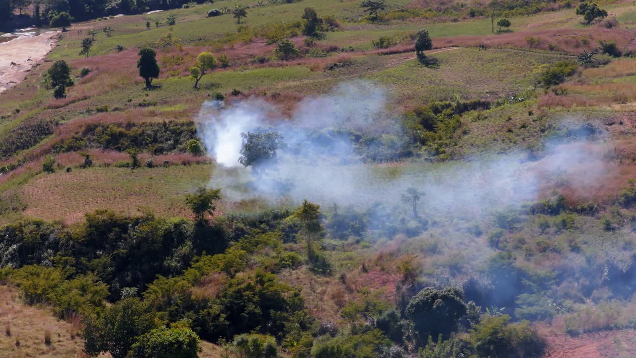 Haiti'de, kömür üretmek için yakılan bitki örtüsüne sahip ormanlık arazi, yerden yükselen yoğun dumanla çevresel tahribatı, arazi temizliğini ve kırsal manzarayı gösteriyor. Havadan yörünge çekimi.