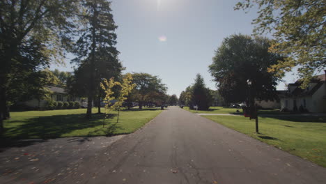 drive along a typical street of an american town on a clear autumn day. view from the windshield of the car