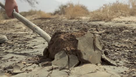 man digging a dry soil with a shovel during day time in the desert, close up