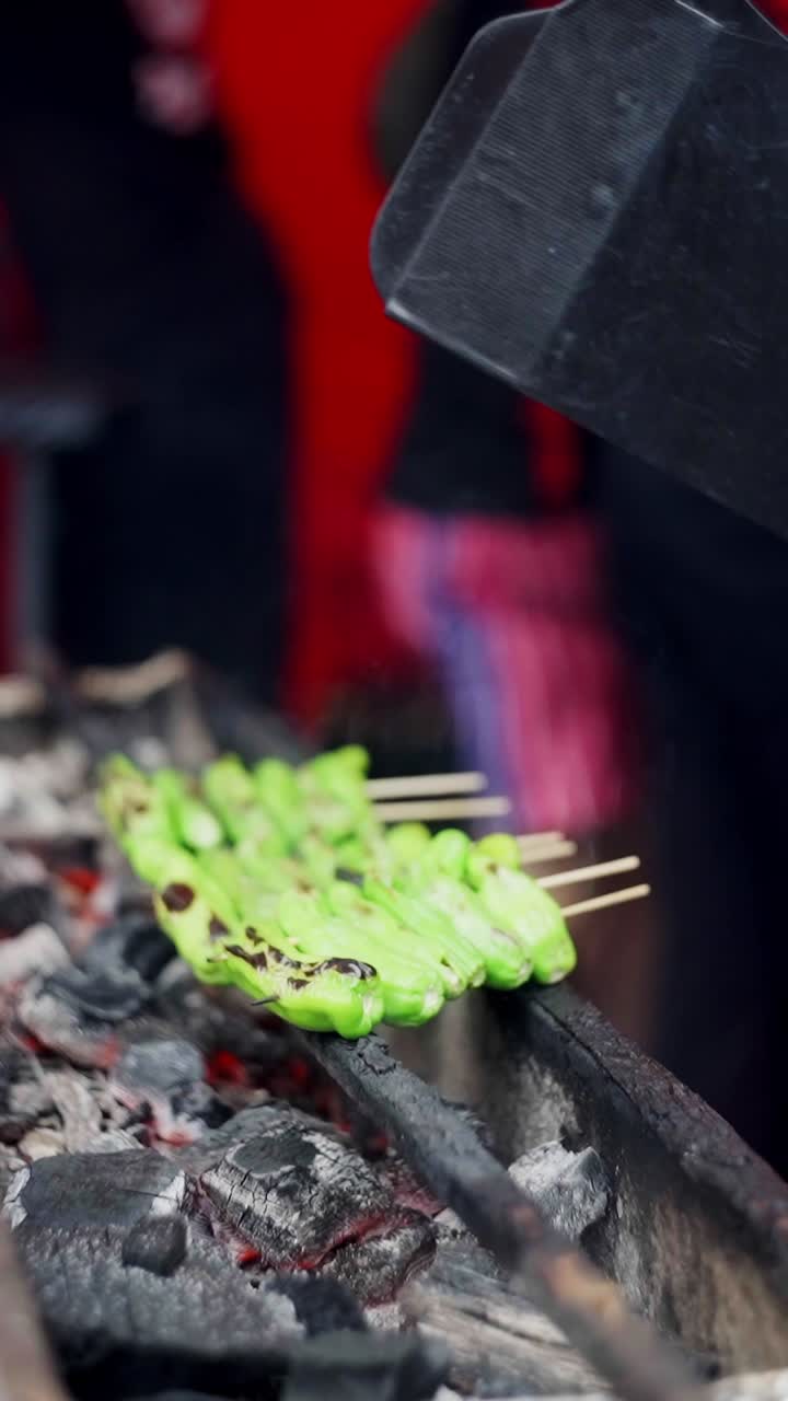 Close up view of Smoky red jalapenos grilled in charcoal in a street food market.