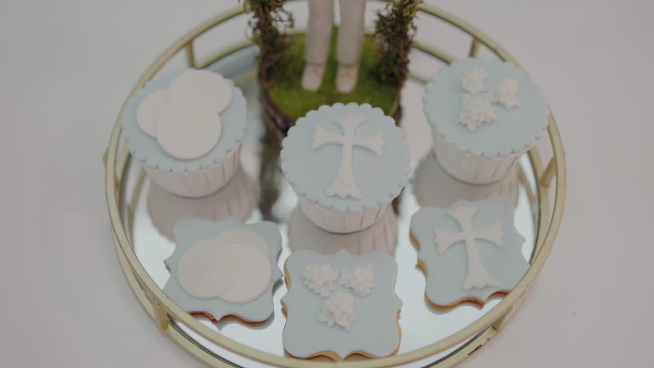 pasteles decorativos de temática religiosa y galletas con diseños de cruz y nubes en una bandeja