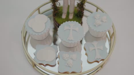 Decorative-religious-themed-cupcakes-and-cookies-with-cross-and-cloud-designs-on-a-tray