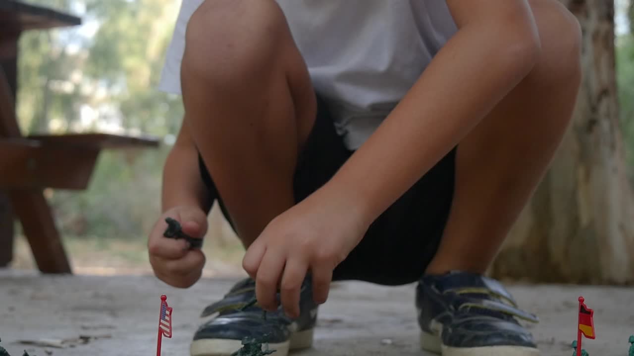 A young boy plays war games with green army men at the park