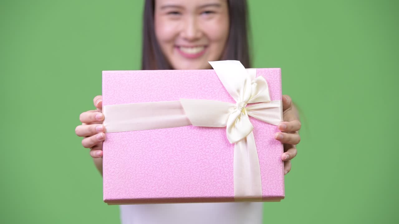 Young beautiful Asian businesswoman giving gift box