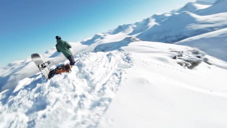 Person-on-top-of-snow-covered-mountain-ready-to-snowboard-down,-aerial-drone-view