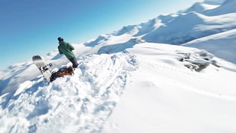 person on top of snow covered mountain ready to snowboard down, aerial drone view