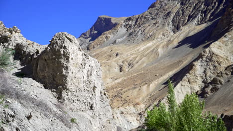 Excursionistas-De-Tiro-Inclinado-Caminando-Por-El-Camino-Junto-A-Una-Cerca,-Hacia-Las-Altas-Montañas