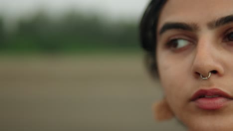 blurry half-face of a woman with nose piercing, overcast mood, close-up, shallow focus