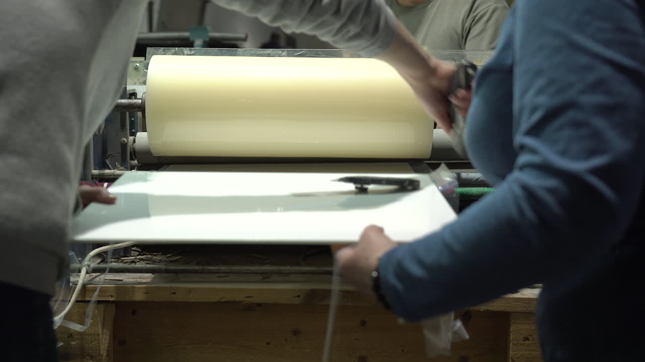 직원들이 칼로 여분의 호일을 자르고 있습니다.