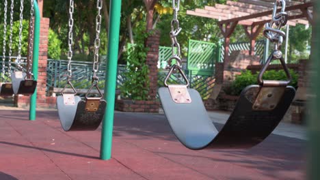 a row of empty swings is seen on a children's playground at a park in hong kong