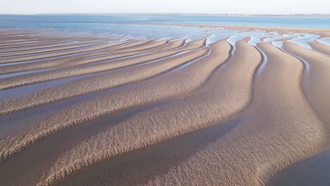 dunas de arena dorada texturizada con líneas principales hasta el borde de las aguas azules