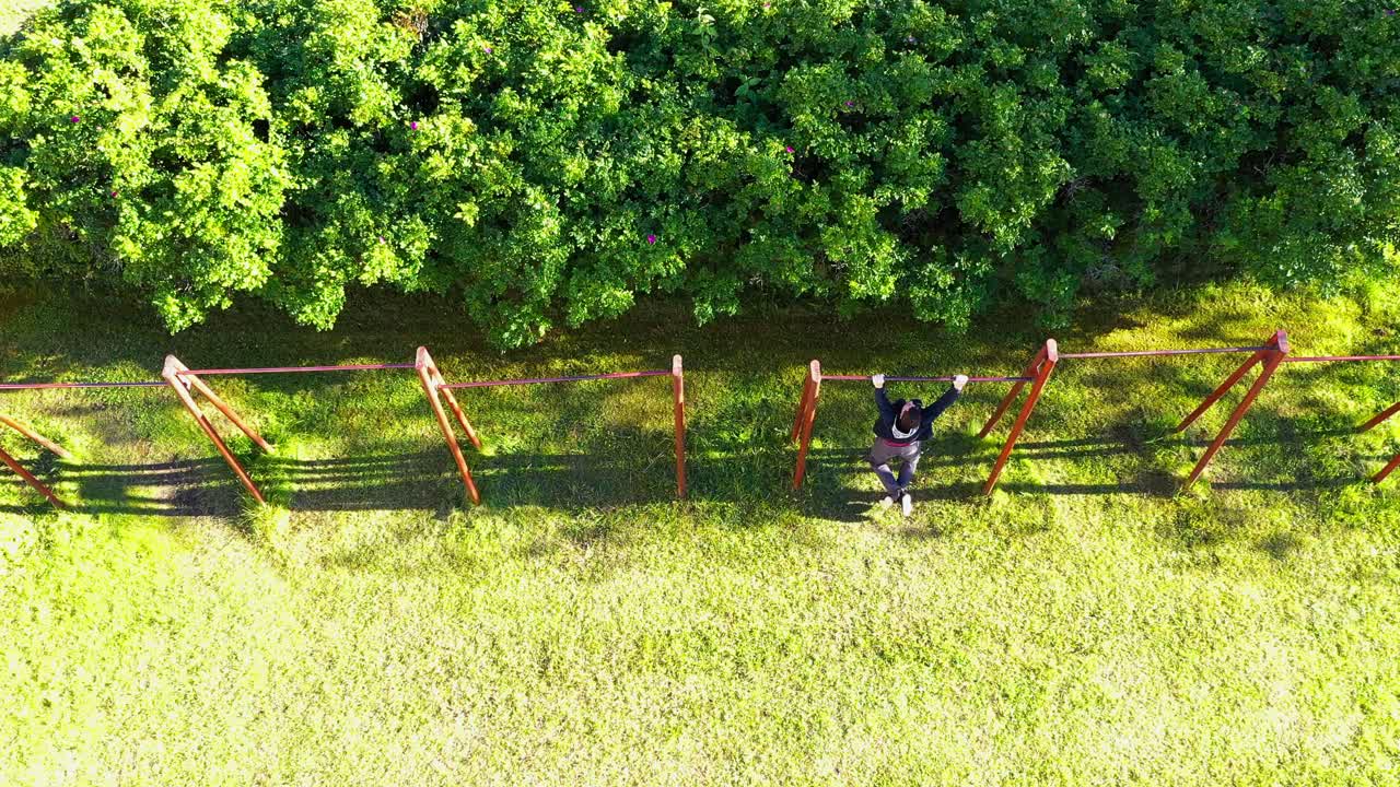 오래 된 소박한 야외 체육관 장비에 풀 업을 하 고 젊은 남자, 하향식 보기