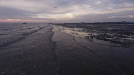 waves coming into the mudflat, track in shot, drone shot, sunset