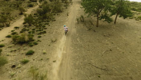 motorcyclist climbs on dusty hill at racing fpv. motocross sportsman rides powerful motorbiker at scenic highland. conquering wilderness on vehicle