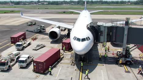 an airplane is being loaded with cargo at a busy airport. ground crew members are actively managing the transportation of containers and equipment to ensure smooth operations during the busy day.