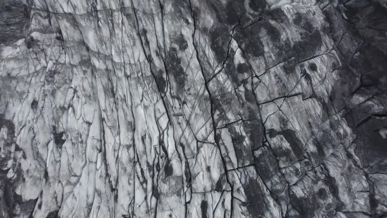 vista aérea de drones girando sobre una superficie cenicienta y oscura del glaciar, en islandia