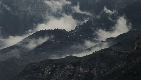 clouds form around a small village on a mountain in greece