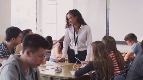 maestra de secundaria hablando con un estudiante sentado en los escritorios durante la lección