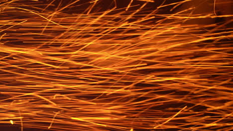 lots of red hot sparkles alongside with white ones thrown at a very good speed. bright ablaze particles at black backdrop.