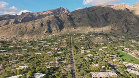Sunny-Catalina-Foothills-in-Tucson-Arizona,-Drone-Shot-of-Neighborhood,-Golf-Course-and-Mountain-Range-with-Blue-Sky-in-Background