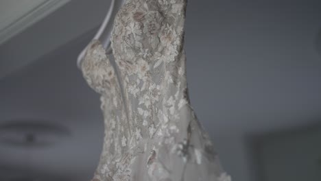 primer plano de un vestido de novia intrincadamente detallado con encaje floral, colgando elegantemente en una percha