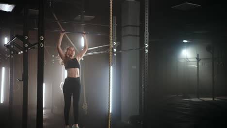 teenage girl in school gym in sporty class doing pull-up on crossbar physical activity for youth