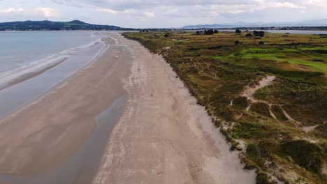 avión no tripulado sobre la playa de portmarnock y el club de golf, howth cabezas en el fondo