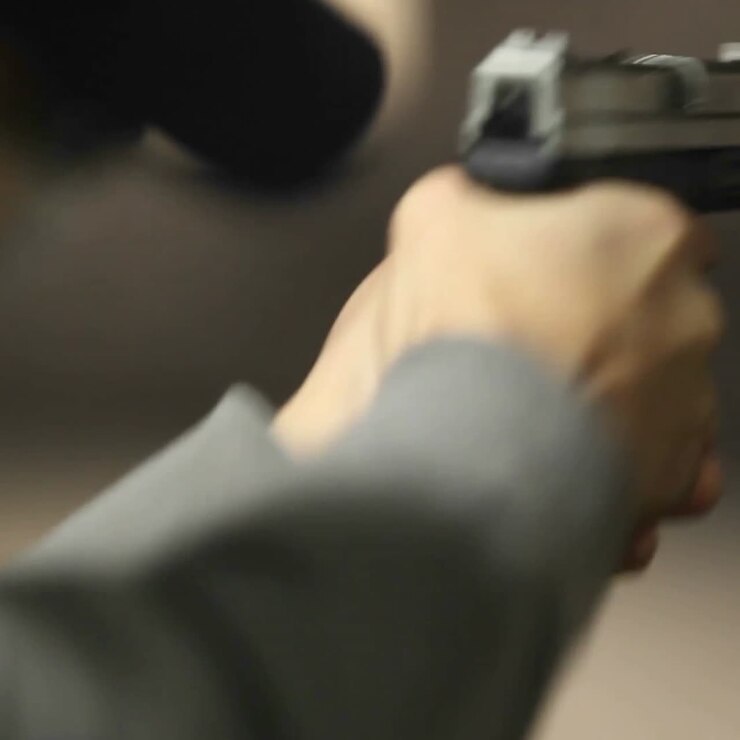 A man fires a hand gun at a target at an indoor shooting range
