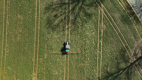 Tractor-tending-to-a-field,-creating-neat-rows,-aerial-perspective---spray-before-season