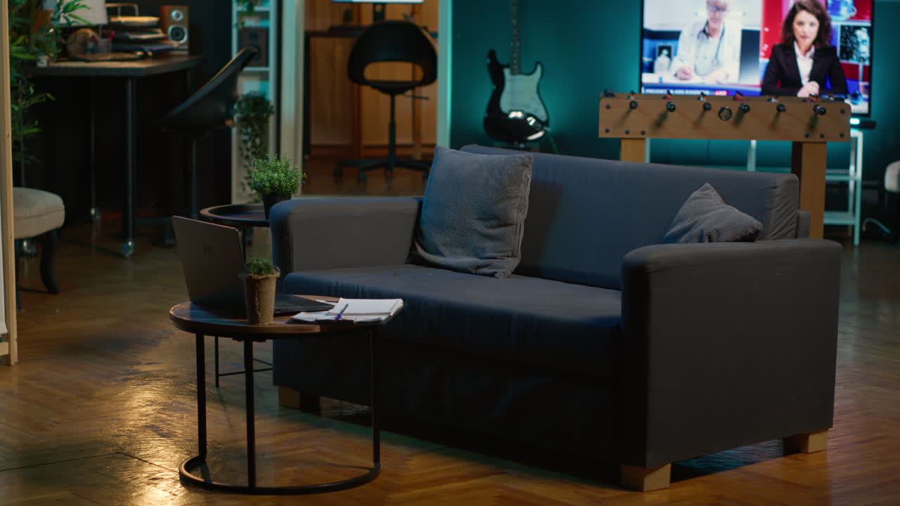 Stylish modern apartment decorated with cool furniture and neon lights, home theatre and setup with big tv for a young adult. Empty loft illuminated and equipped with electronics, comfortable space.