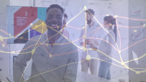 smiling man in office with data processing animation over colleagues discussing