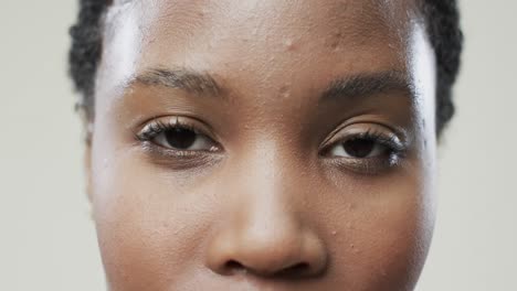 eyes of african american woman with short dark hair on beige background, slow motion