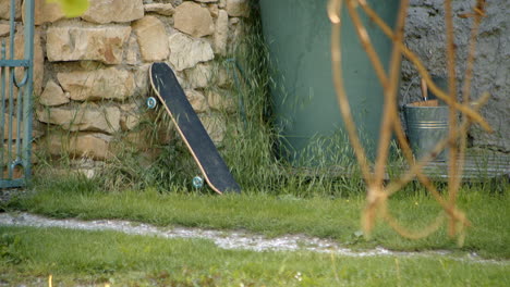 unused skateboard leans against stone wall in quiet yard