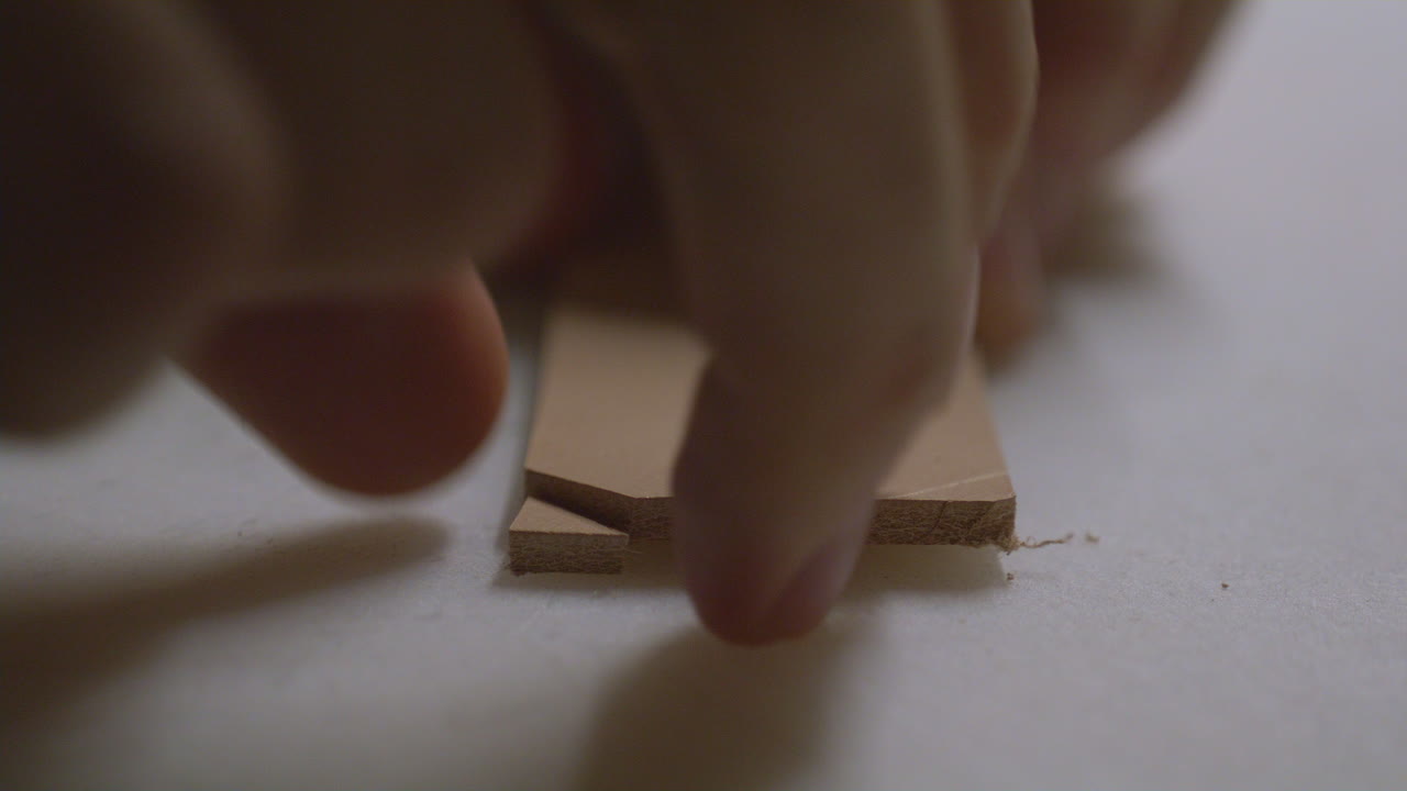 A close-up view of a sharp chisel precisely slicing through a piece of thick leather.
