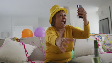 una anciana afroamericana animada con champán haciendo una llamada de video por teléfono inteligente en la víspera de año nuevo