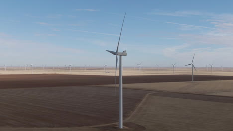 Aerial-tracking-shot-of-shadowy-wind-turbine-amid-a-large-wind-farm-in-north-Texas,-USA