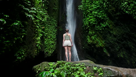 slomo disparado desde la parte trasera de una mujer viajera caucásica mirando hacia arriba a las cataratas de leke leke