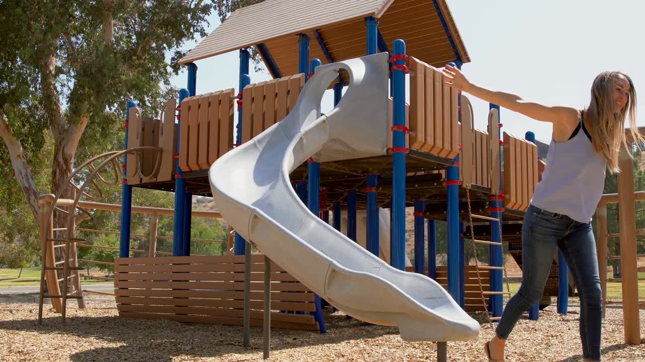 mujer divirtiéndose bajando por un tobogán en un parque
