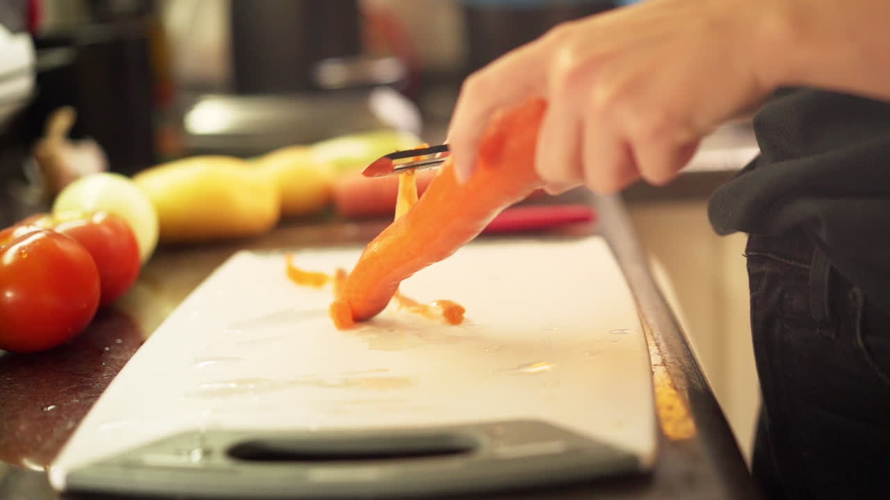 cerrar las manos femeninas pelando zanahorias en la cocina a cámara lenta