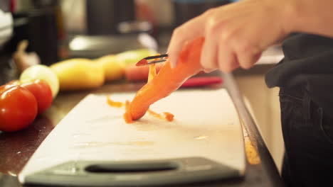 close up female hands peeling carrots in the kitchen in slow motion