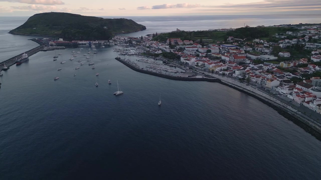 Vista Aerea al Tramonto, Marina di Horta sull'Isola di Faial, Azzorre, Portogallo, che Mostra il Porto, il Lungomare, le Barche Ormeggiate e la Calda Luce Serale sull'Oceano Atlantico