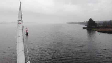 sailing vessel sails between a red beacon and green buoy on a fairway on a cloudy day in the netherlands