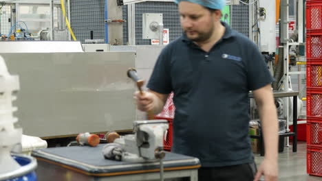 factory worker walking at workplace to pick up mallet from working table