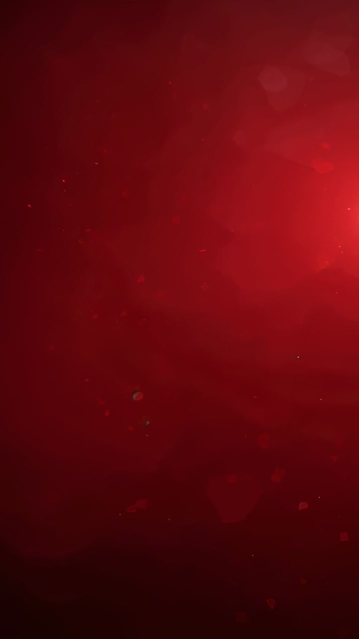 Video verticale: luce incandescente verticale che emerge con gradiente rosso scuro in studio, punti che fluttuano per il set